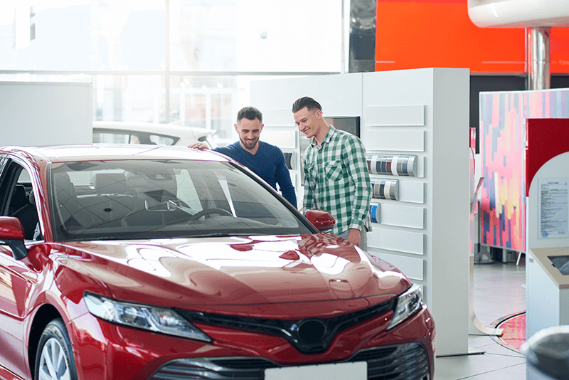 Fotografía de dos personas comprando un coche representando la bajada de matriculaciones